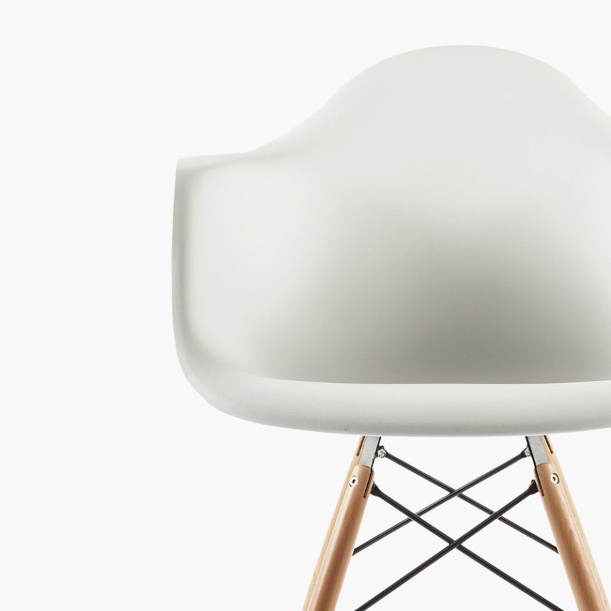 Modern white designer chair with wooden legs and black metal supports on a white background.