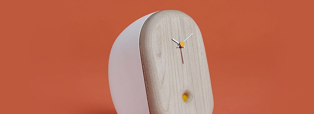 A minimalist wooden wall clock with white frame accents against an orange background.